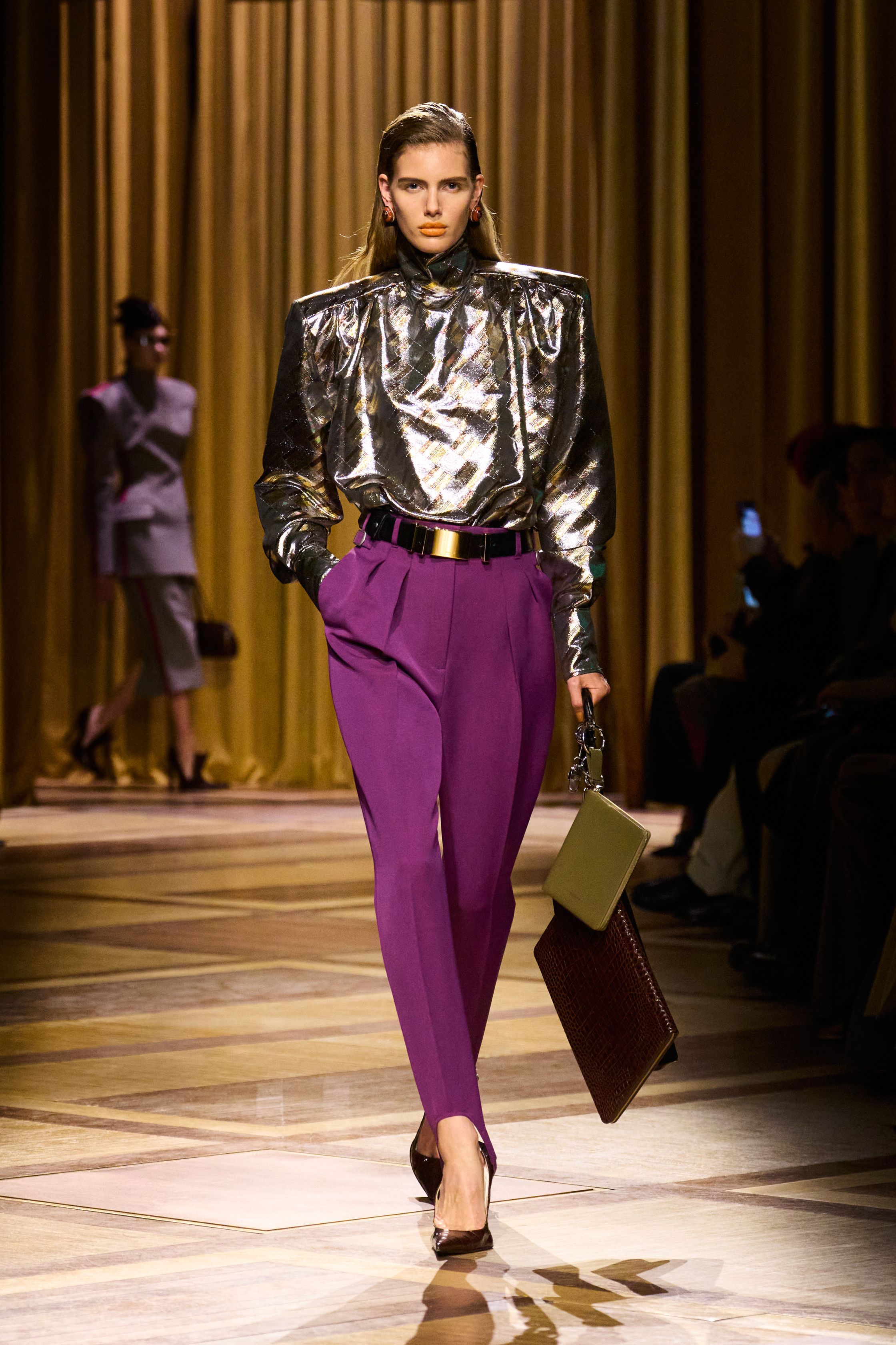 Mugler 本季继续强化品牌最核心的雕塑性感：极端肩线、收紧腰部与流畅长裤塑造出未来感女性轮廓。紫色权力套装、金属光泽衬衫和皮革裙装让整场秀既强势又华丽，仿佛科幻电影中的都市女主角-顽石频道趋势研究